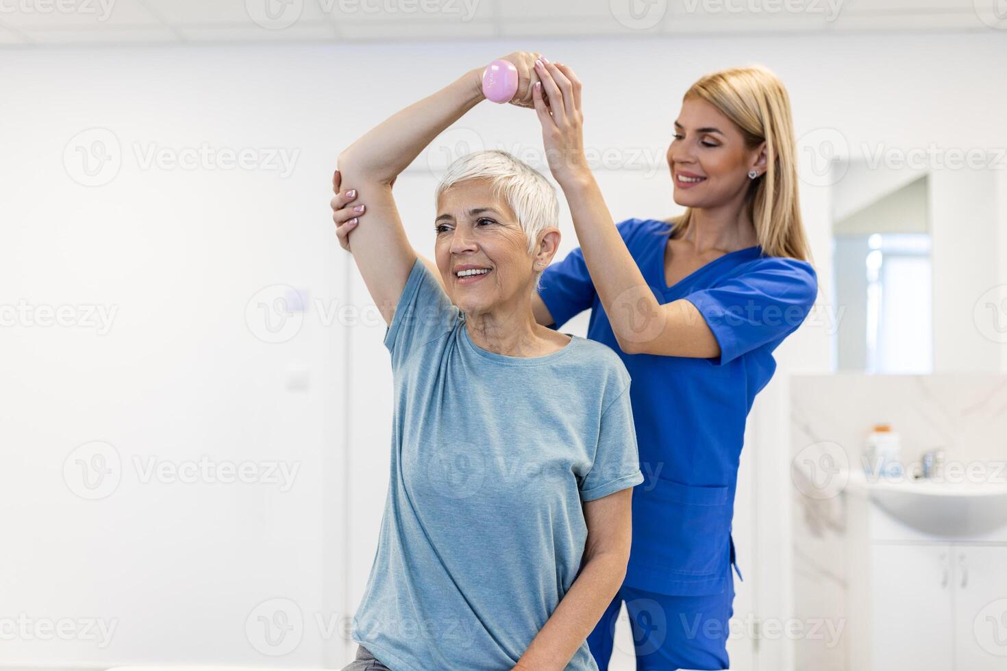 Physiotherapist woman giving exercise with dumbbell treatment About Arm and Shoulder of senior female patient Physical therapy concept photo