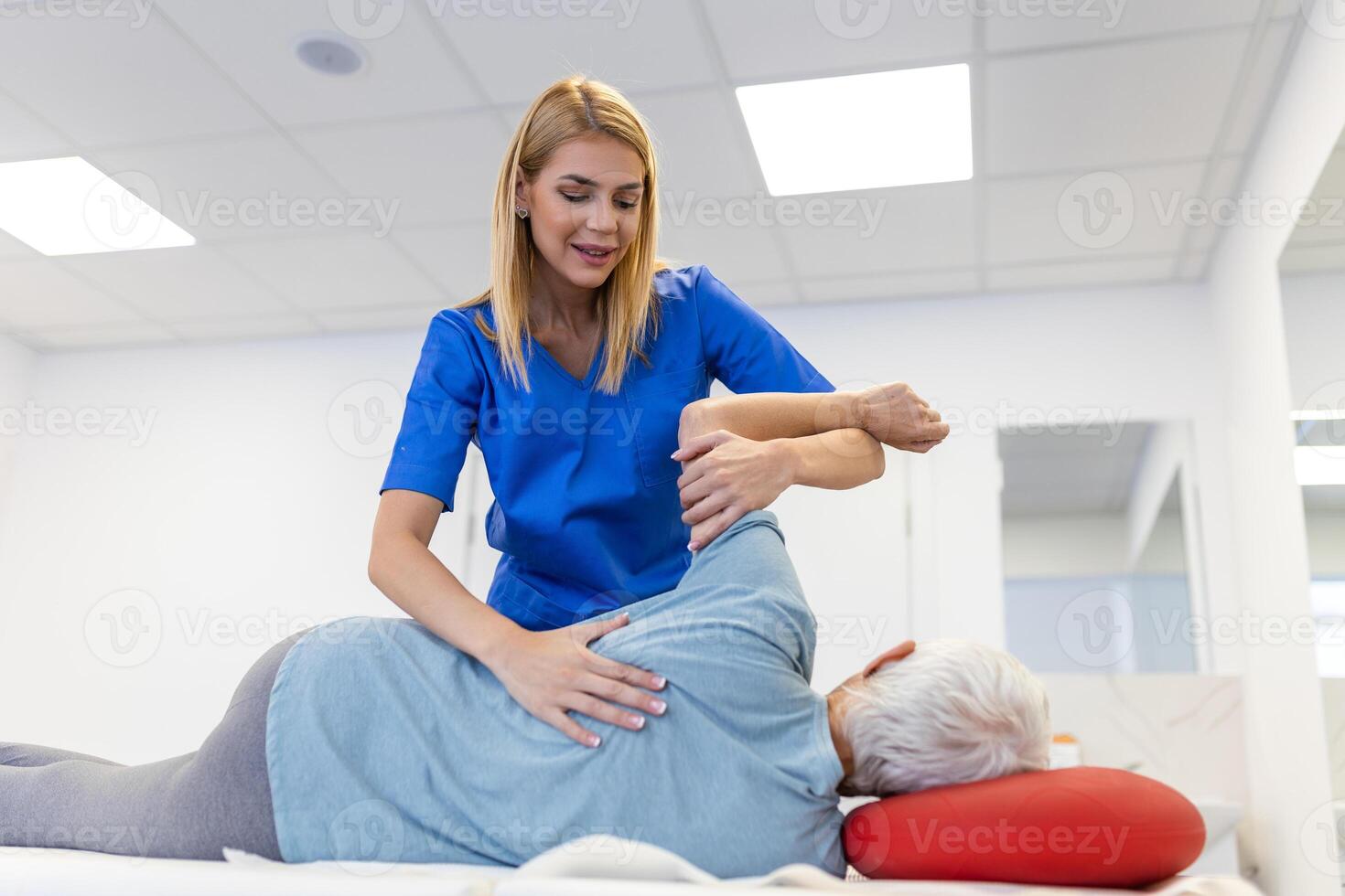 Doctor or physiotherapist helps to heal a senior woman's back. and give advice within the rehabilitation center. Concept of physical rehabilitation. photo