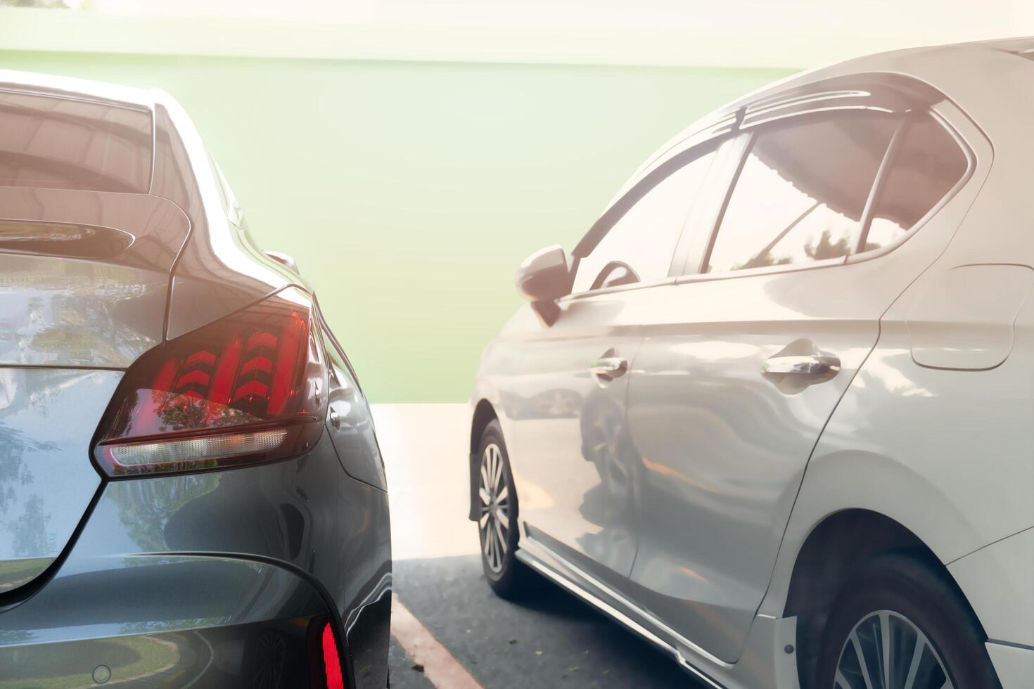 Rear side of car in the garage. with blurred of white car in the beside. Background of wall green building with light. photo