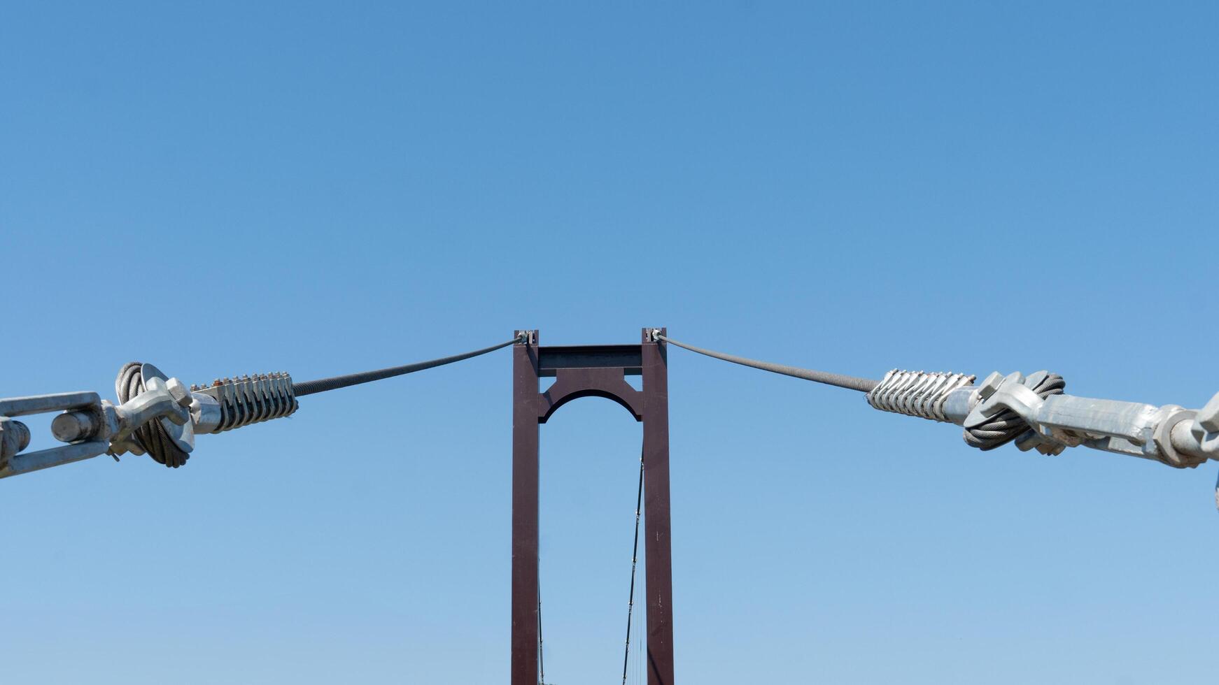 Large wire ropes that hold the bridge's steel structure. Background of clear sky. photo