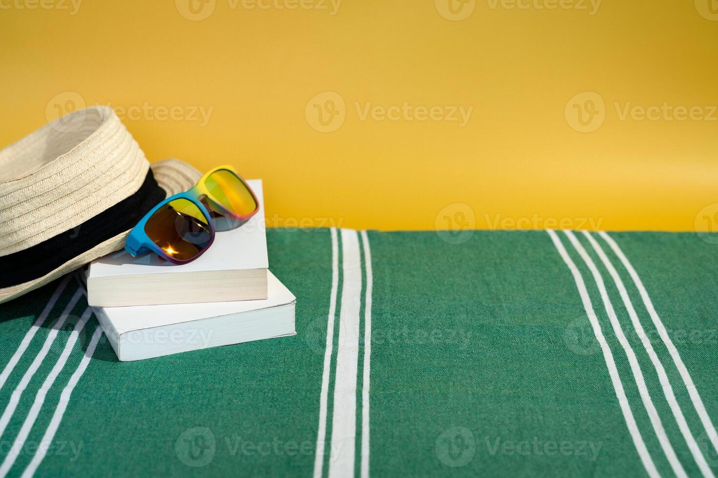 sun hat sunglasses and books on beach towel photo