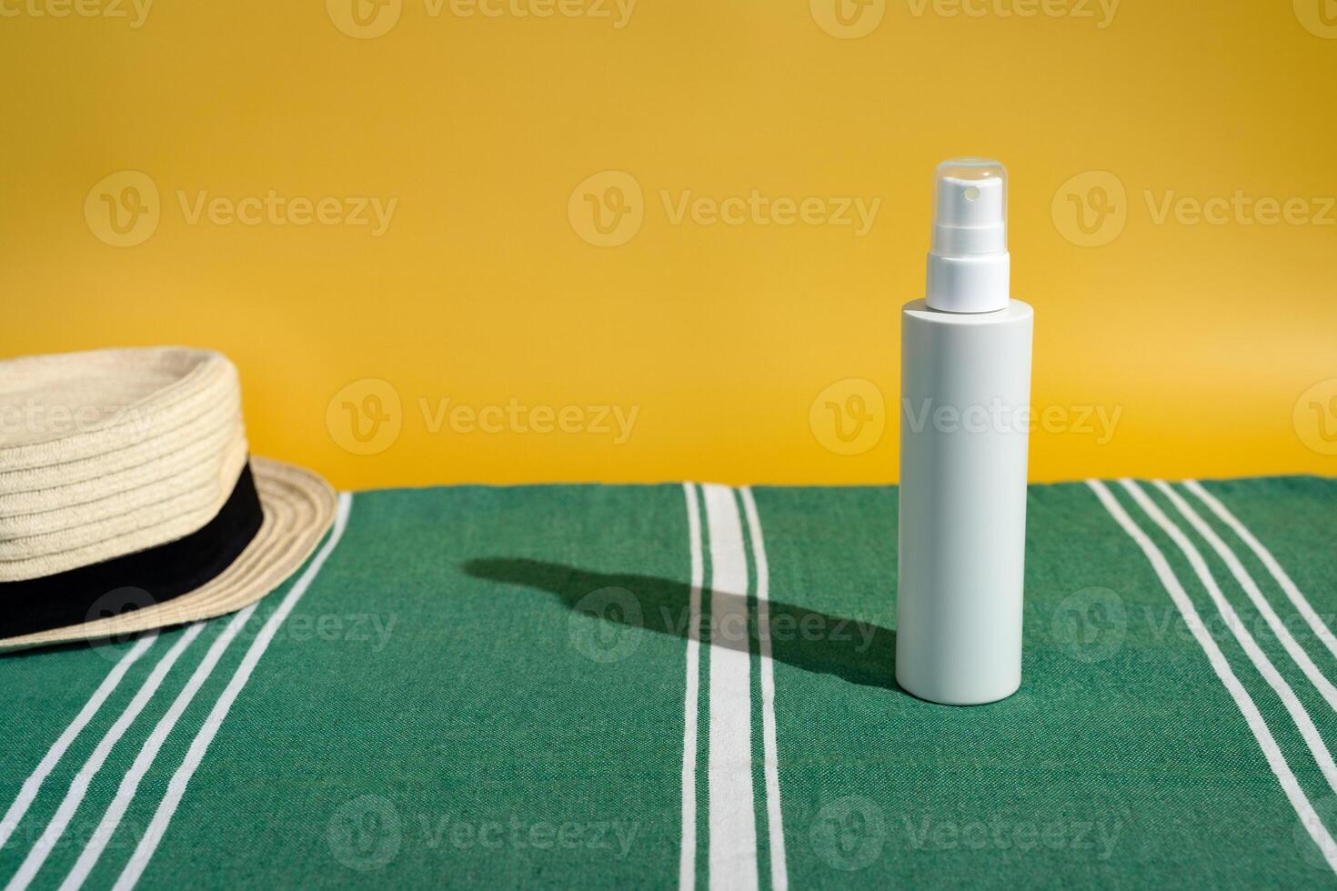 Blank sunscreen bottle sun hat on beach towel photo