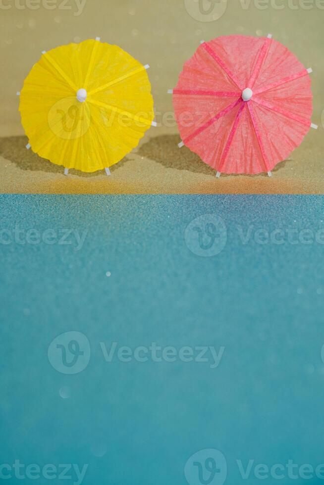 Abstract beach with glitter paper sand and water and cocktail umbrellas photo