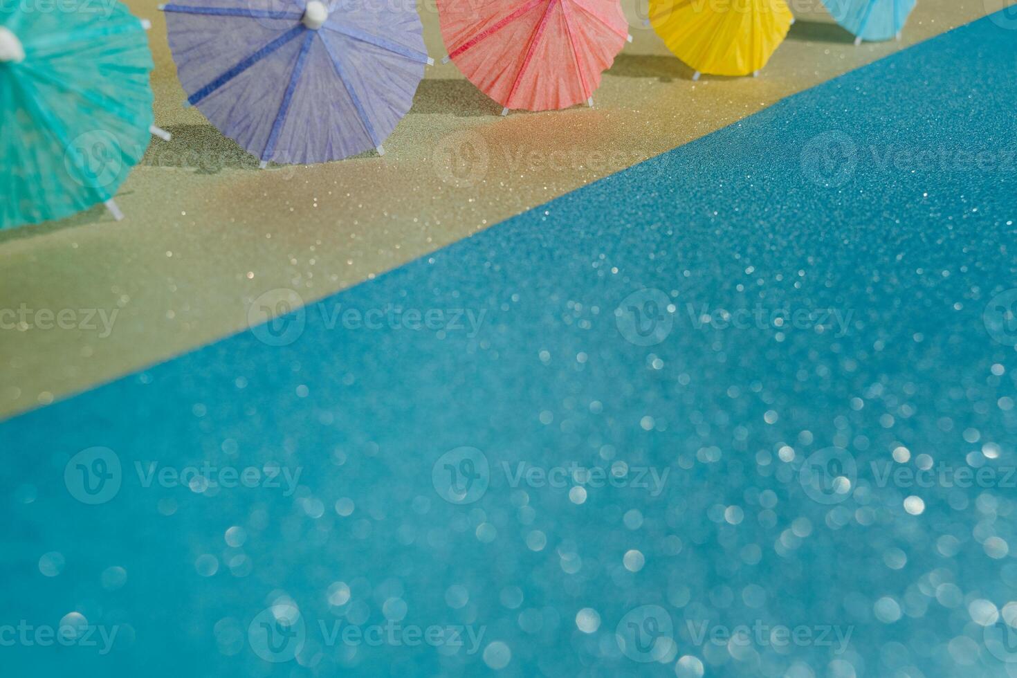 Abstract beach with glitter paper sand and water and cocktail umbrellas photo