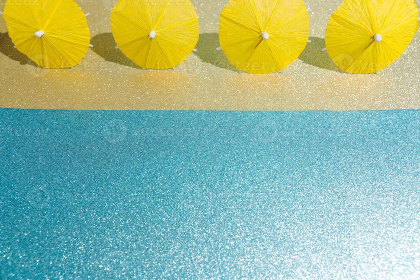 Abstract beach with glitter paper sand and water and cocktail umbrellas photo