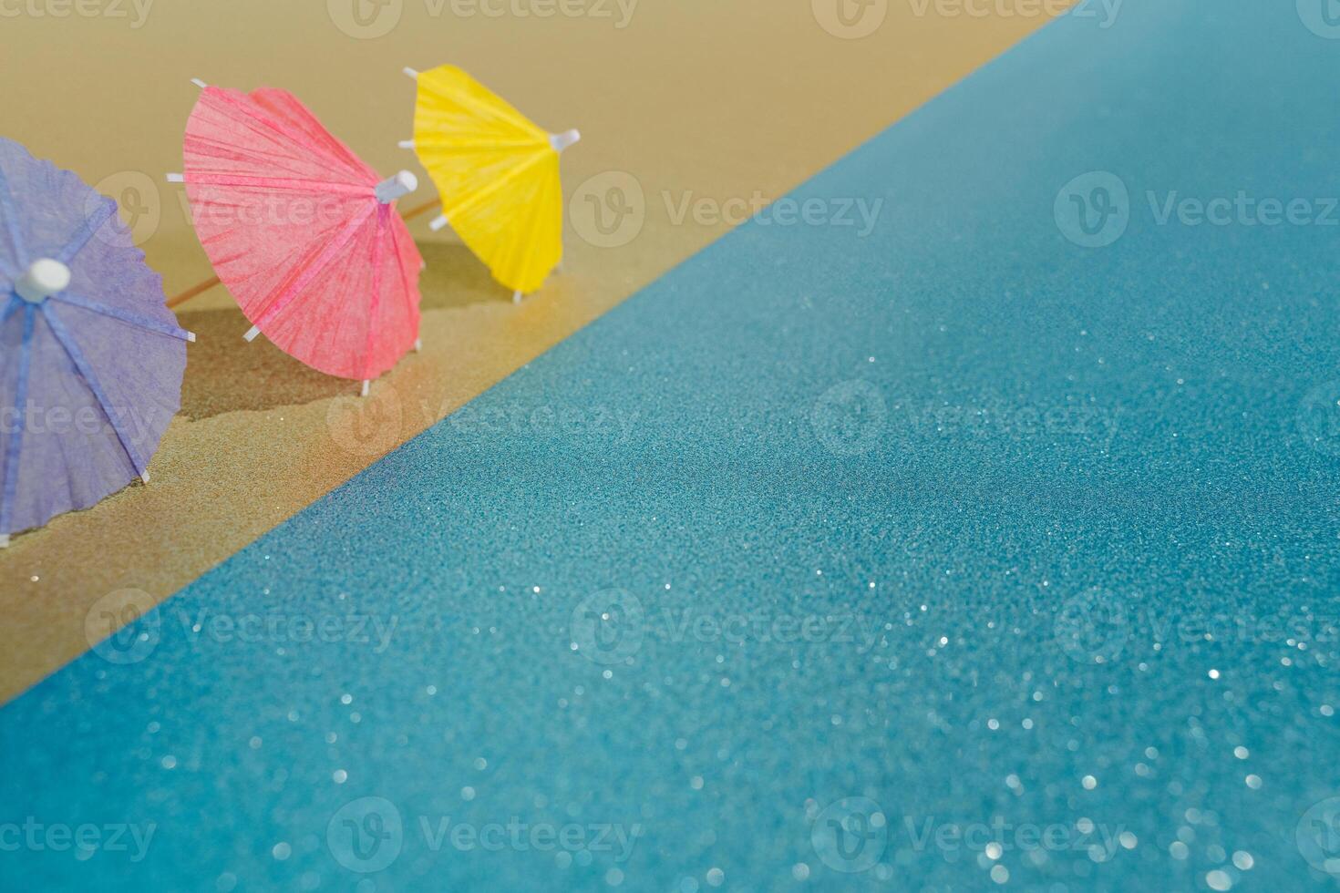 Abstract beach with glitter paper sand and water and cocktail umbrellas photo