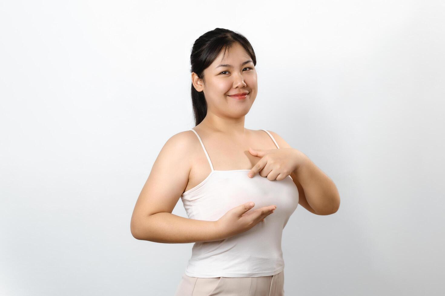 Asian woman checking lumps on her breast for signs of breast cancer on white background. photo