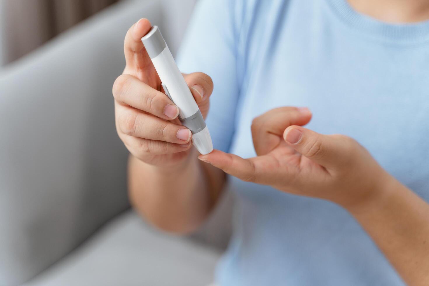 asiático mujer utilizando lanceta en dedo para comprobación sangre azúcar nivel por glucosa metro, diabetes. foto