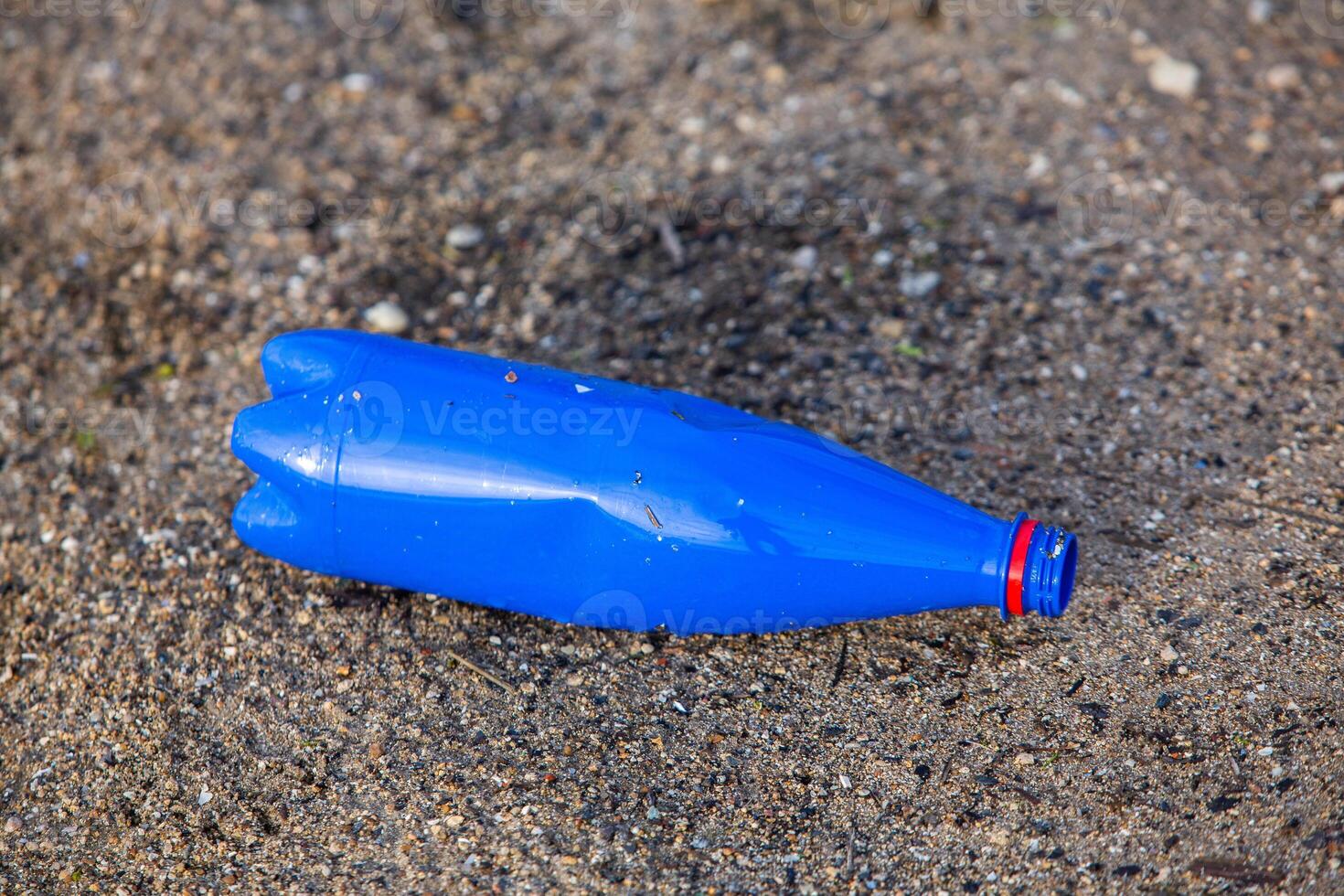 Plastic bottle on the shore of the lake. Environmental pollution. Plastic waste on the beach. photo