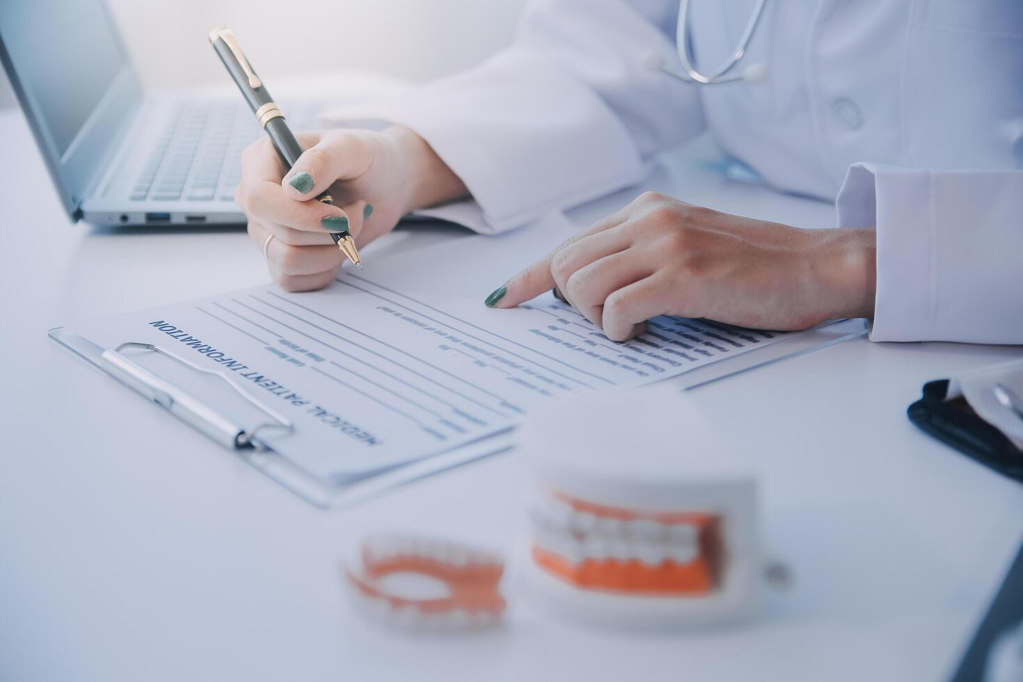 los dentistas están discutiendo problemas dentales al informar la imagen de rayos X en la pantalla del portátil a los pacientes. foto