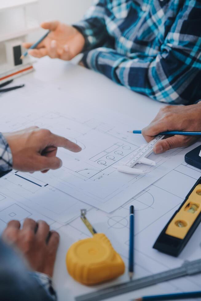 engineer people meeting working and pointing at a drawings in office for discussing. Engineering tools and construction concept. photo