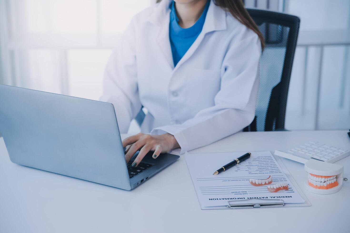 los dentistas están discutiendo problemas dentales al informar la imagen de rayos X en la pantalla del portátil a los pacientes. foto