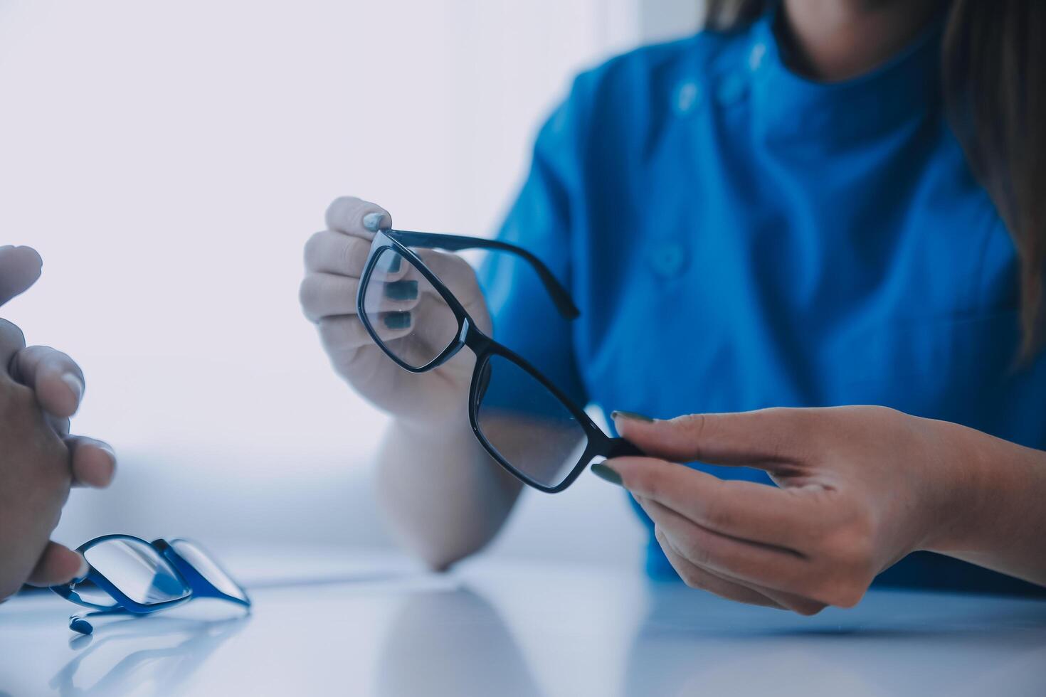 Close-up of Asian female doctor talking with elderly patient showing eyeball model and explaining eye disease in hospital photo