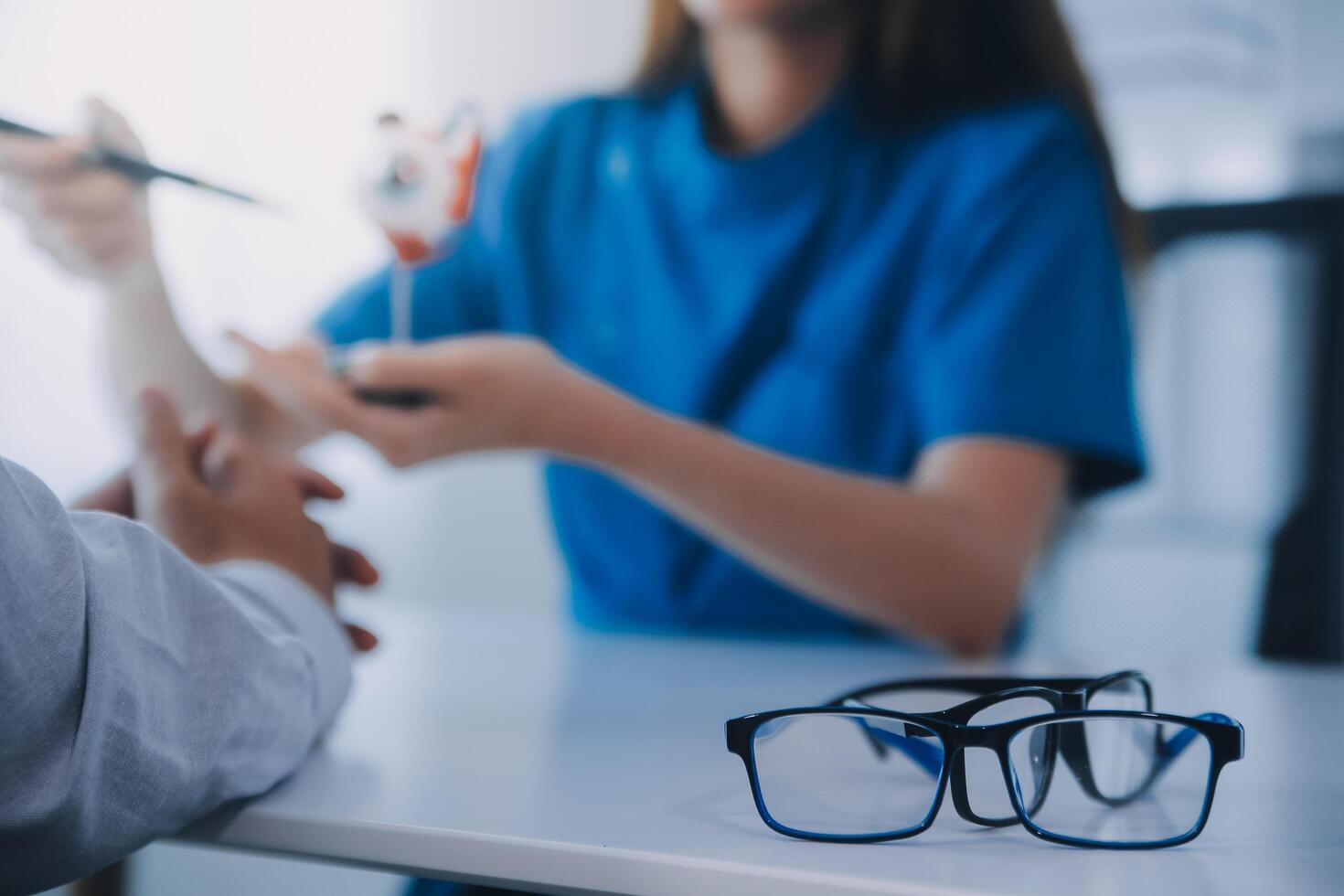 Close-up of Asian female doctor talking with elderly patient showing eyeball model and explaining eye disease in hospital photo