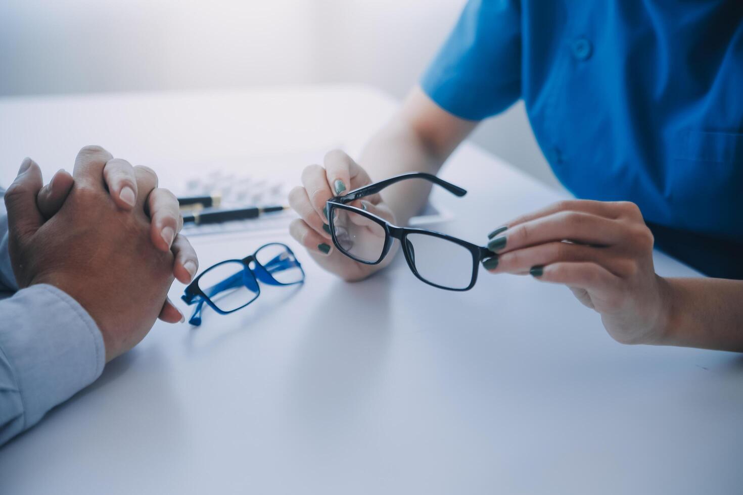 Close-up of Asian female doctor talking with elderly patient showing eyeball model and explaining eye disease in hospital photo