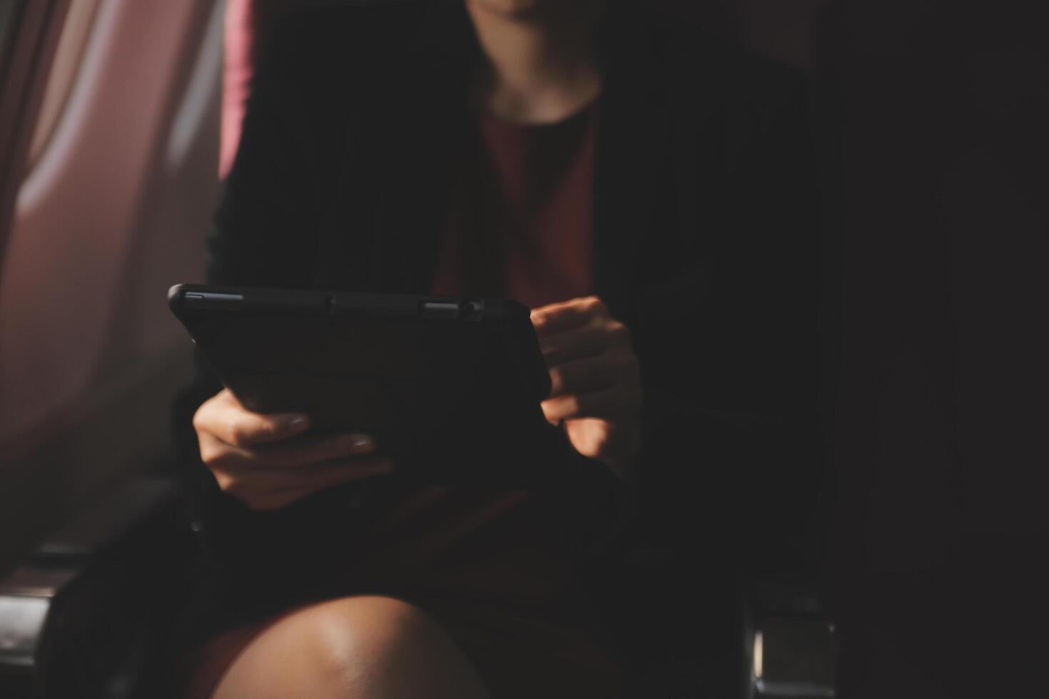 rubia hembra turista comprobación entrante notificación en teléfono inteligente sentado en asiento de avión con netbook.joven mujer de negocios compartir medios de comunicación desde teléfono en ordenador portátil computadora durante avión vuelo foto