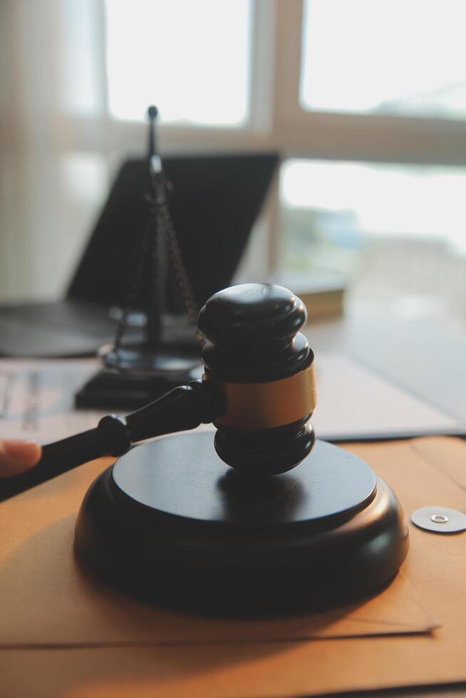 Business and lawyers discussing contract papers with brass scale on desk in office. Law, legal services, advice, justice and law concept picture with film grain effect photo