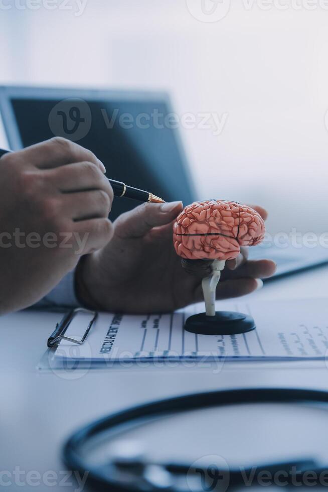 Doctor explaining brain functions to patient on model in office. photo