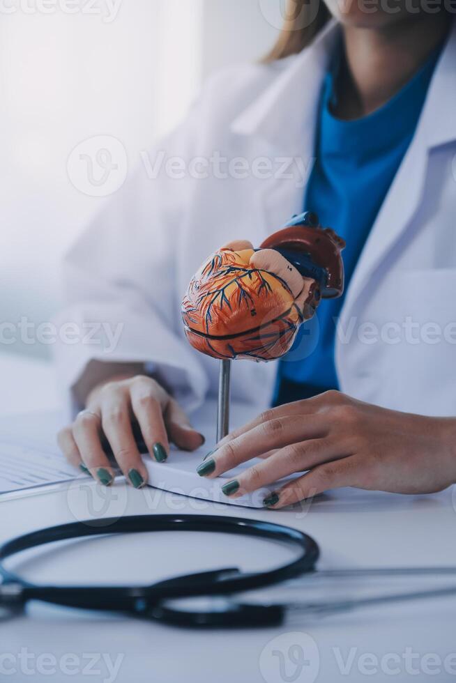 Doctor explaining heart to elderly patient. Doctor explaining the heart model. Doctors pen point to a model of the heart photo