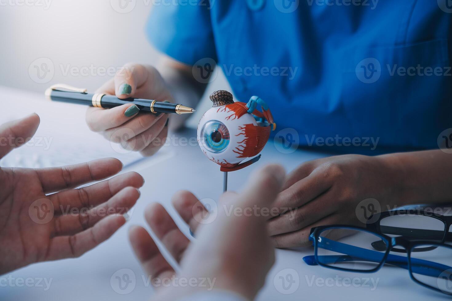 de cerca de asiático hembra médico hablando con mayor paciente demostración globo ocular modelo y explicando ojo enfermedad en hospital foto