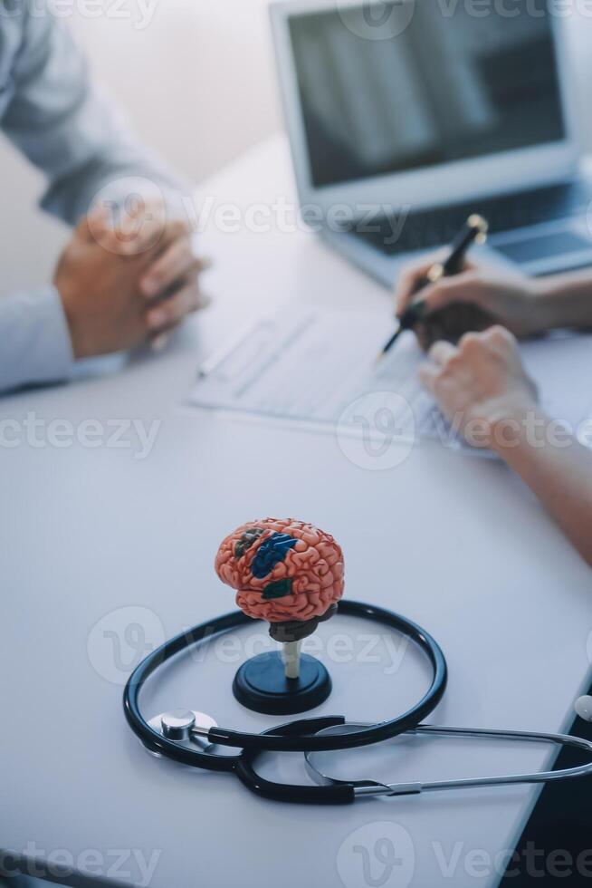 Doctor explaining brain functions to patient on model in office. photo