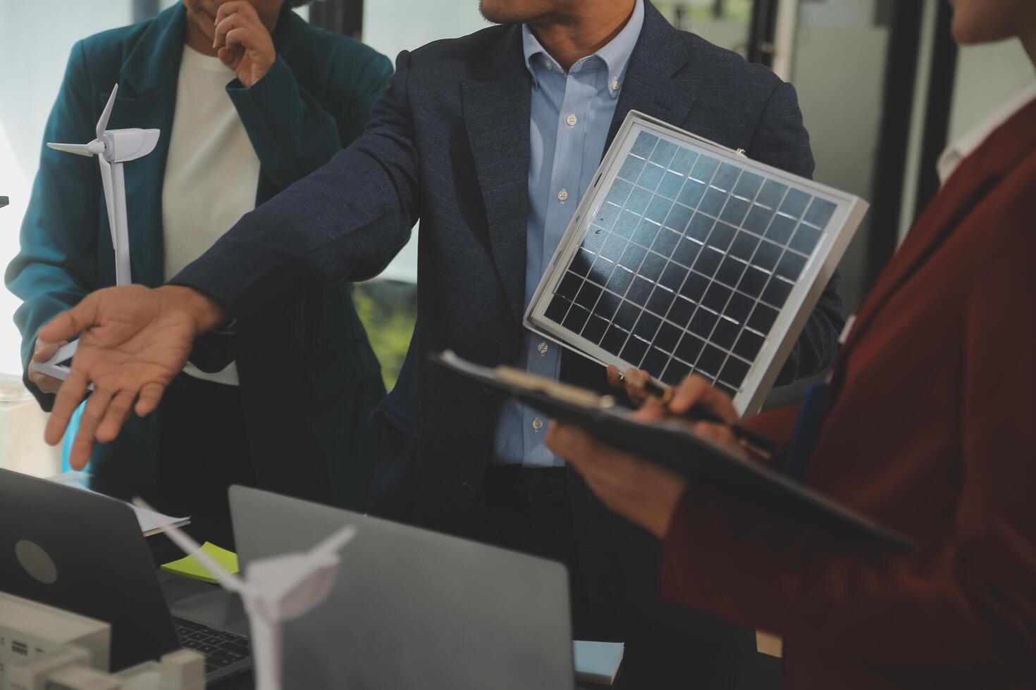 Close-up at tablet, Engineers pointing at tablet with their hands. To jointly design the use of renewable energy with wind and solar energy. Concept of using renewable energy. photo