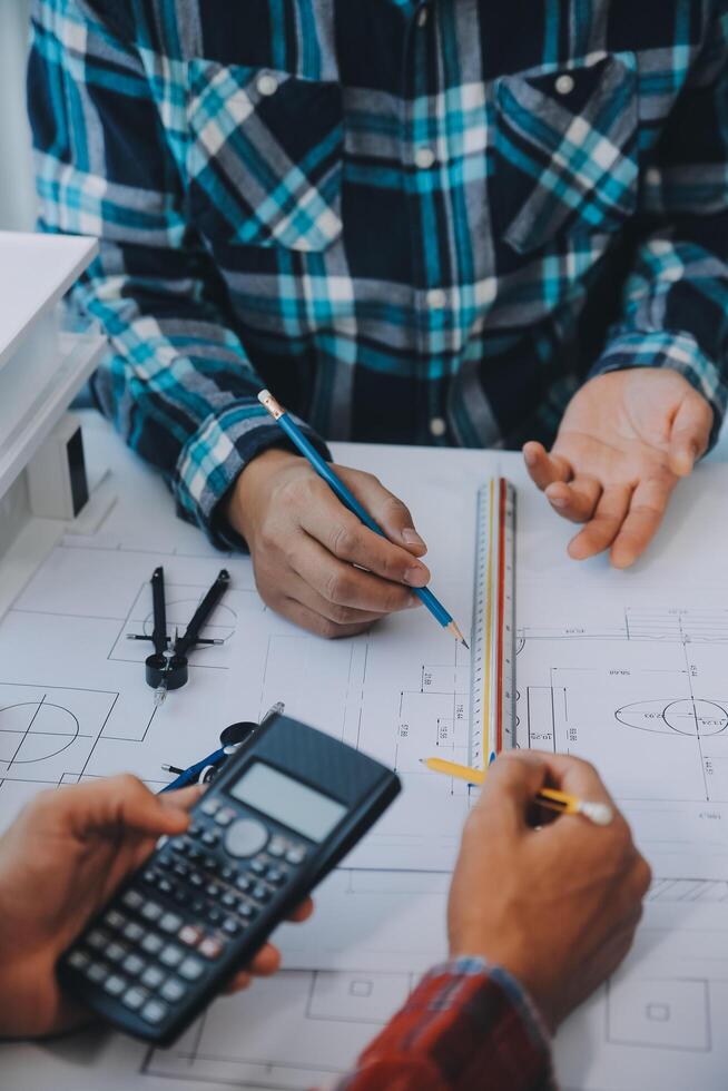 engineer people meeting working and pointing at a drawings in office for discussing. Engineering tools and construction concept. photo