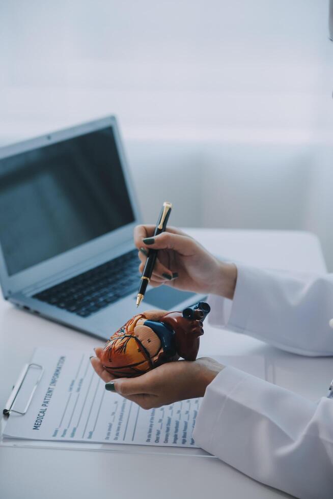 Doctor explaining heart to elderly patient. Doctor explaining the heart model. Doctors pen point to a model of the heart photo