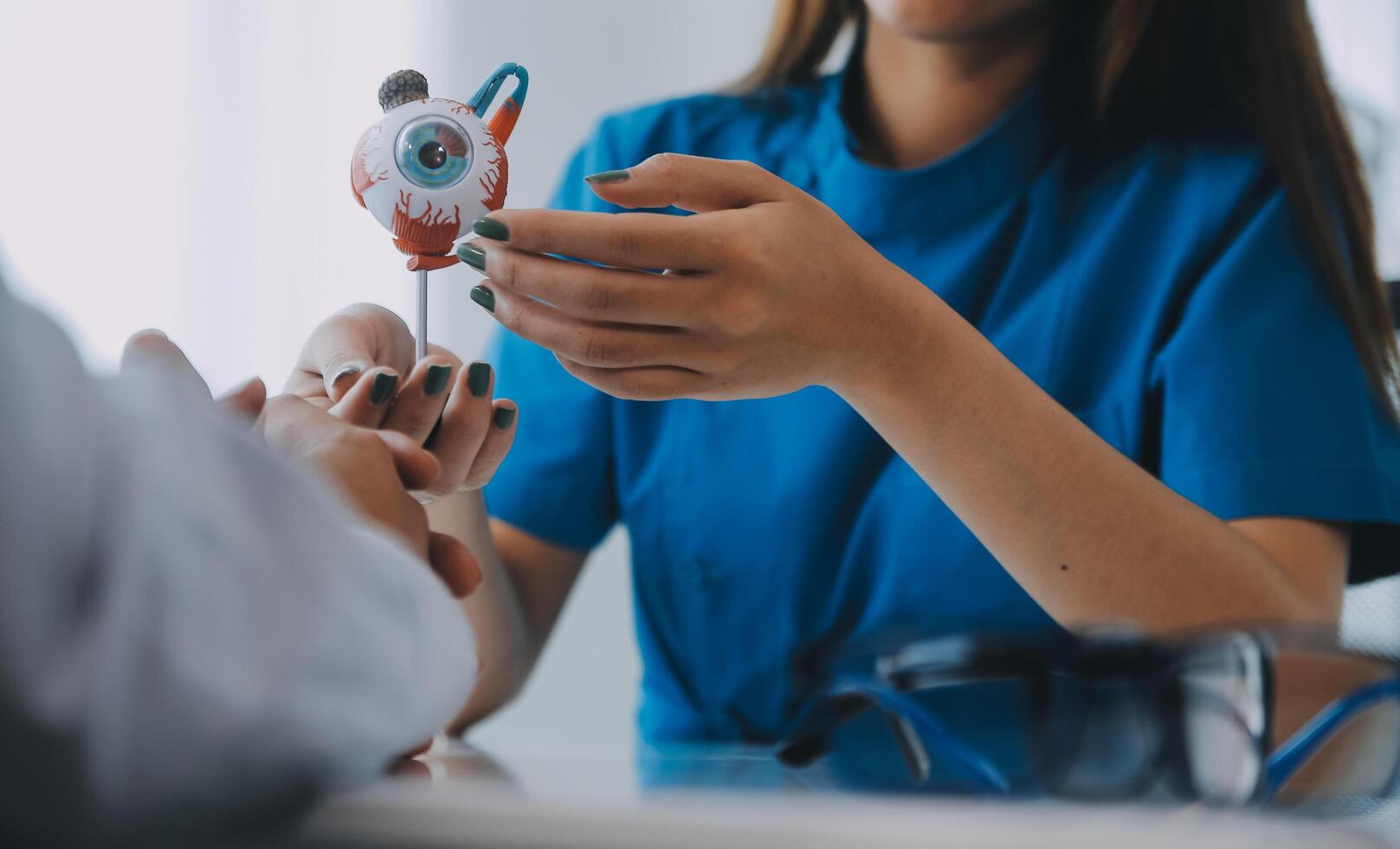 Close-up of Asian female doctor talking with elderly patient showing eyeball model and explaining eye disease in hospital photo