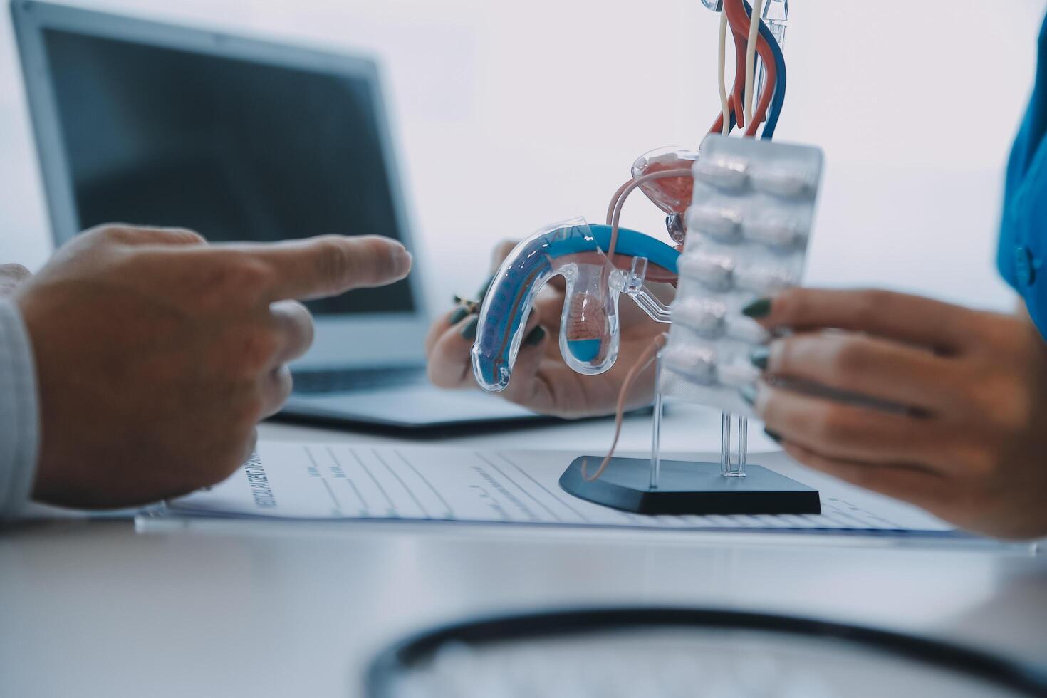 Doctor uses anatomical model to explain male urinary system. Model labeled with parts, doctor points and explains how they work together for urinary function, ensuring patient comprehension. photo