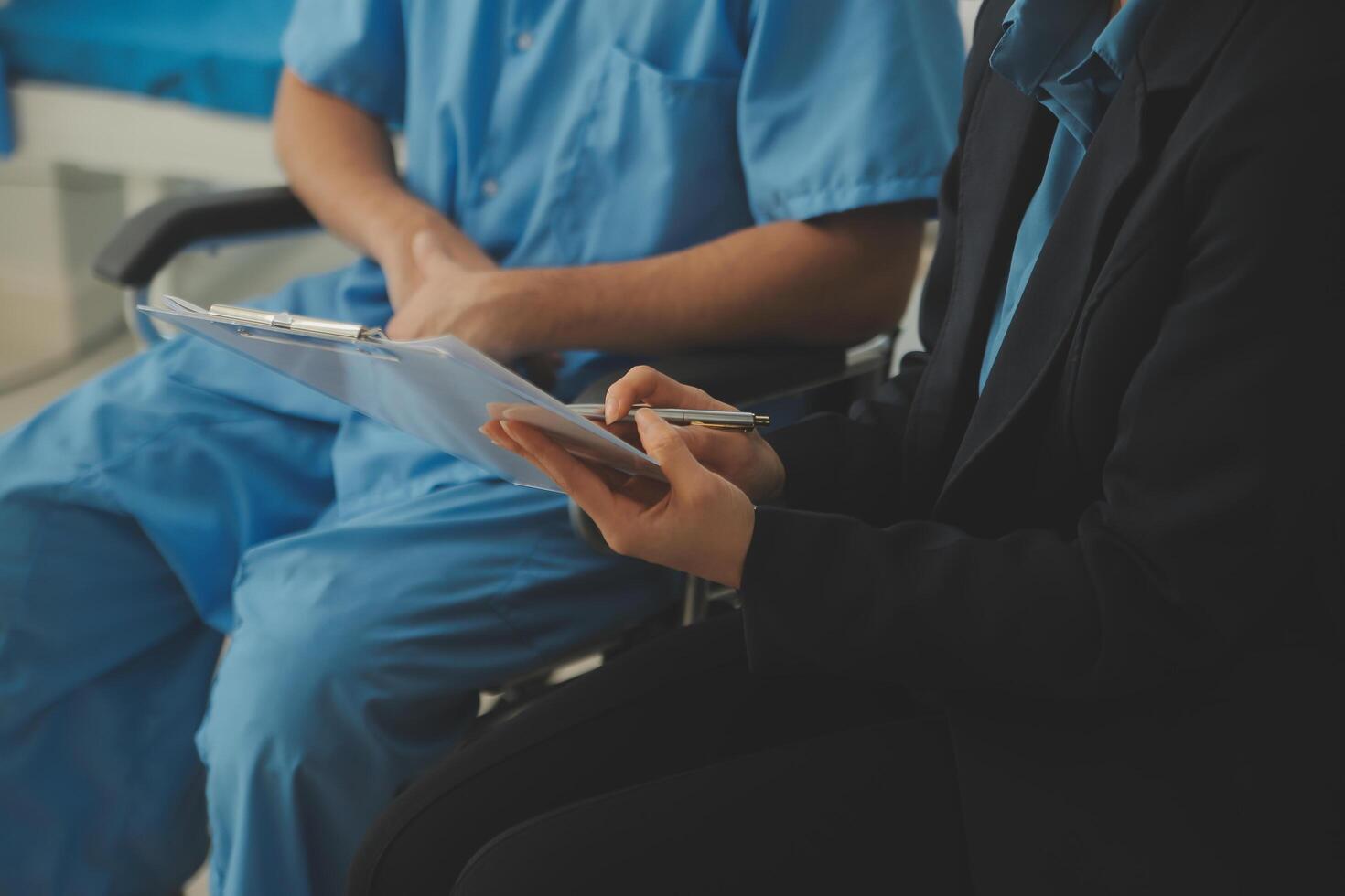 Midsection of female nurse checking blood pressure of woman sitting on wheelchair in clinic photo