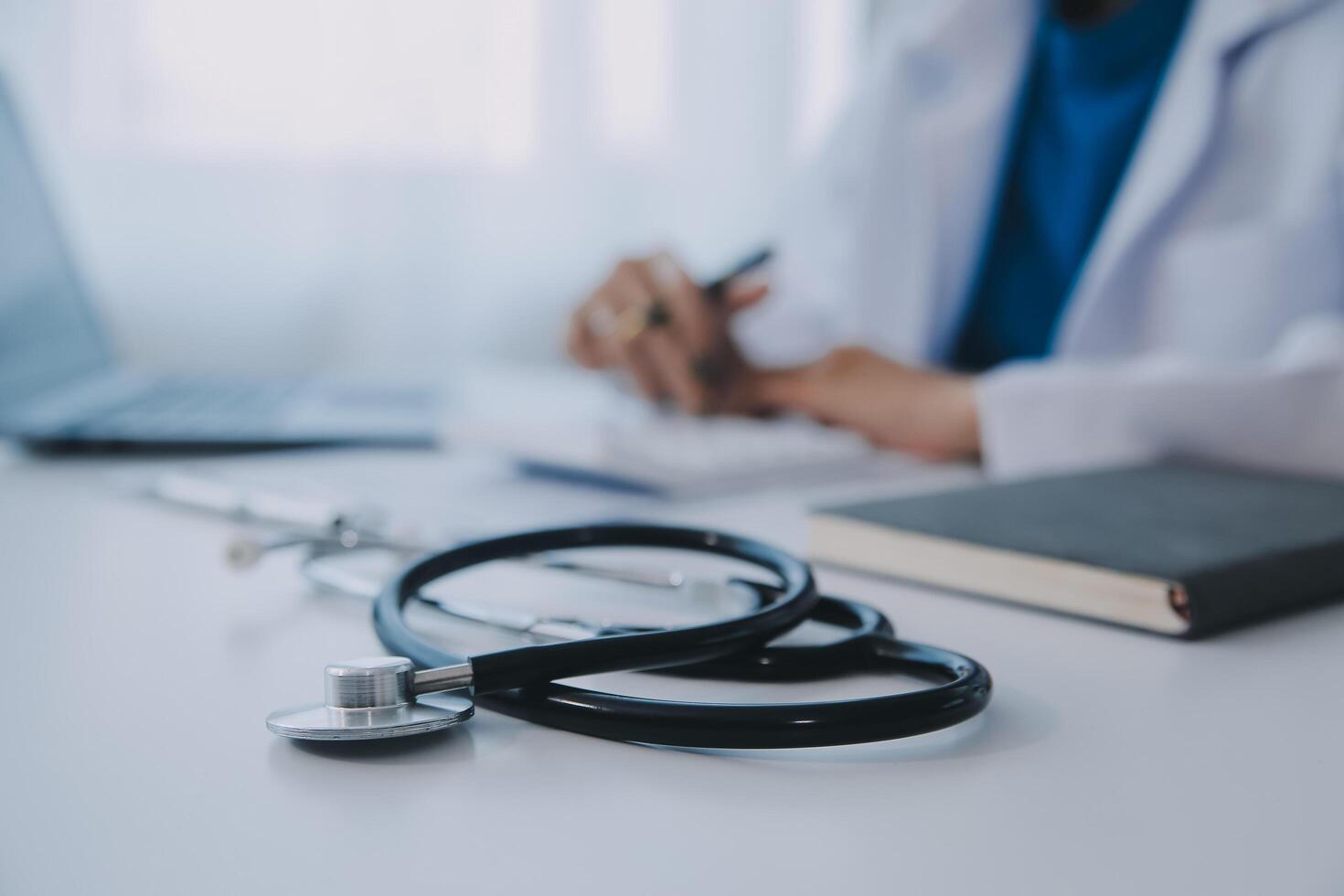 médico y paciente sentado a el escritorio en clínica oficina. el atención es en hembra médico manos relleno arriba el medicación historia grabar forma, cerca arriba. medicina concepto foto