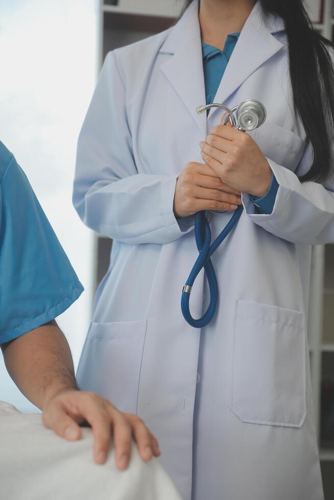 joven médico es utilizando un estetoscopio escucha a el latido del corazón de el paciente. Disparo de un hembra médico dando un masculino paciente un cheque arriba foto