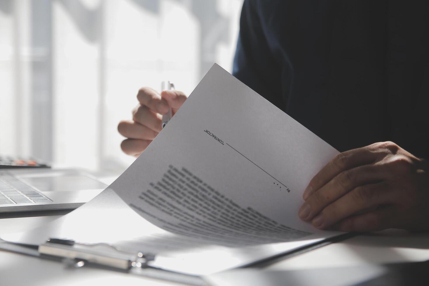 Asian businessman reviewing document reports at office workplace with computer laptop. legal expert, professional lawyer reading and checking financial documents or insurance contract photo