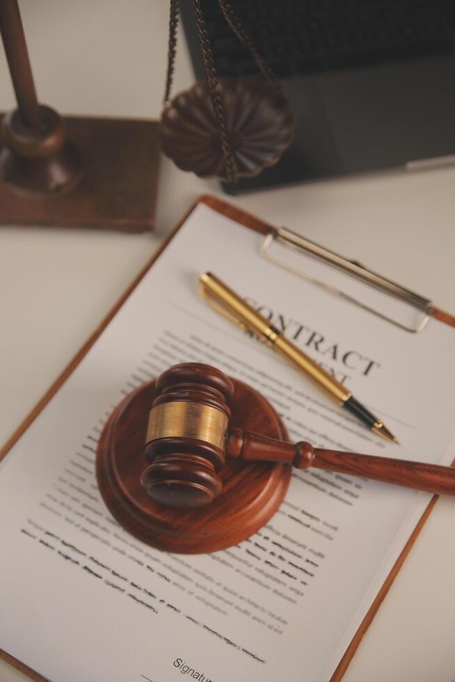 image of judge's hammer, scales lady of justice, law book, laptop computer and contract documents with pen concept of law and justice. photo
