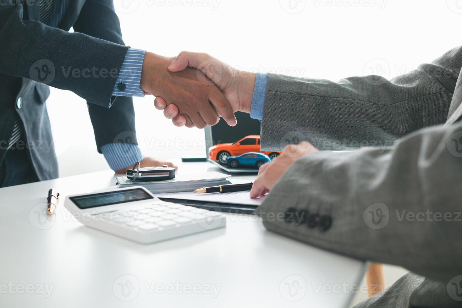 customer and car dealer shake hands after agreeing to sales contract before making contract payment and handing over car keys to customer. concept of handshake between customers and car dealers. photo