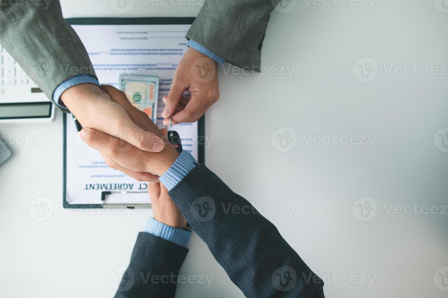 customer and car dealer shake hands after agreeing to sales contract before making contract payment and handing over car keys to customer. concept of handshake between customers and car dealers. photo