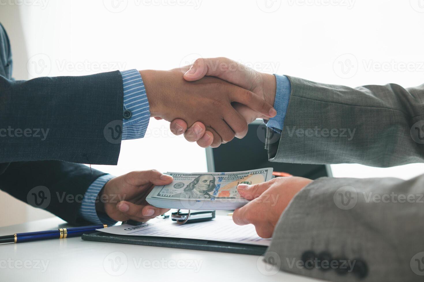 customer and car dealer shake hands after agreeing to sales contract before making contract payment and handing over car keys to customer. concept of handshake between customers and car dealers. photo