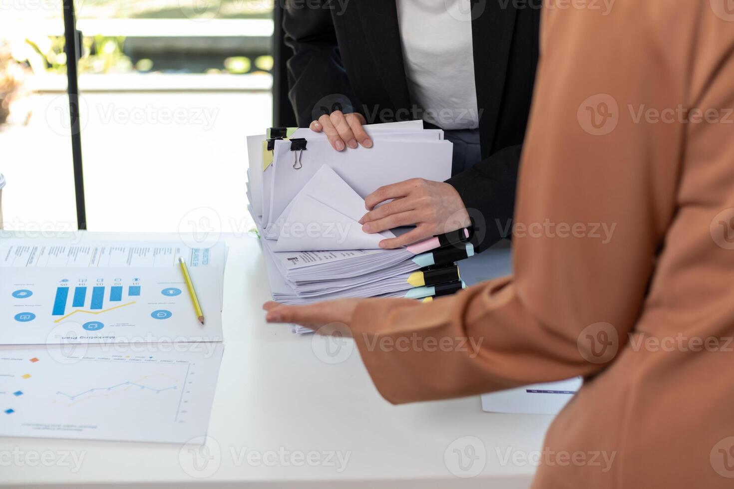 A young secretary receives a pile of documents to find important information for the company manager to use in a meeting. The concept of finding important documents from piles of overlapping documents photo