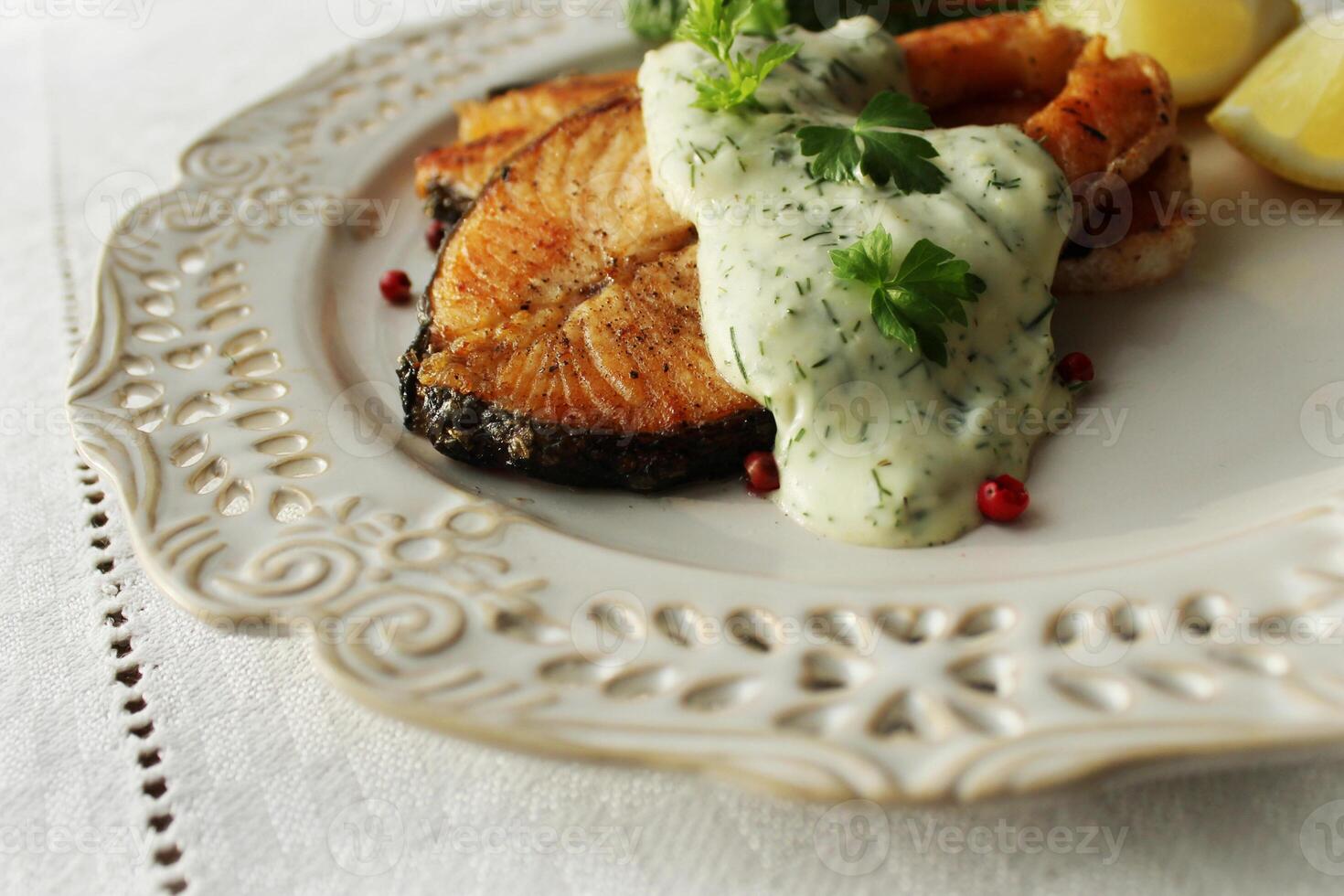 Salmon. Grilled salmon steak with sauce and lemoni on white plate photo