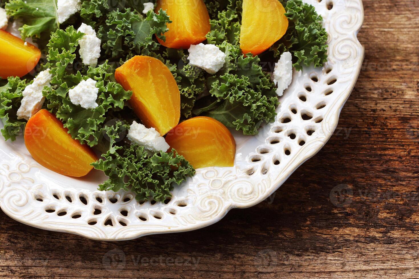 Golden beet salad with fresh kale lettuce, feta cheese on wooden background photo