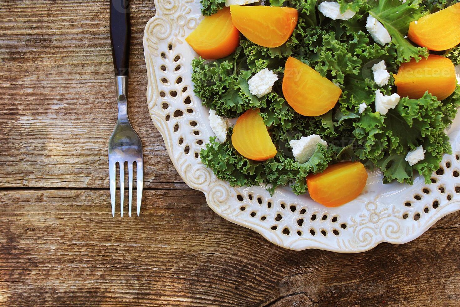 Healthy Beet Salad with fresh kale lettuce, nuts, feta cheese on wooden background. Top view photo