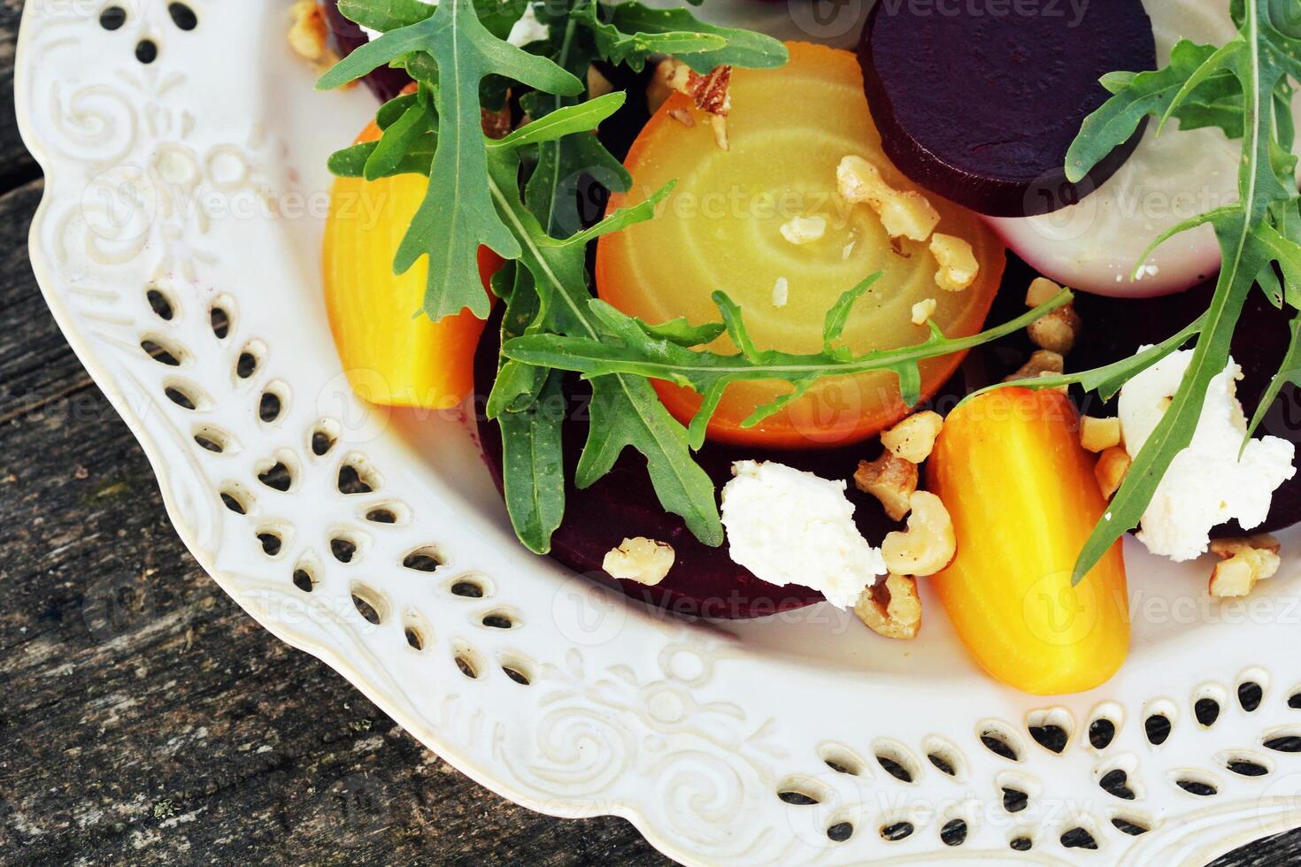 Healthy Beet Salad with red, white, golden beets, arugula, nuts, feta cheese on wooden background photo