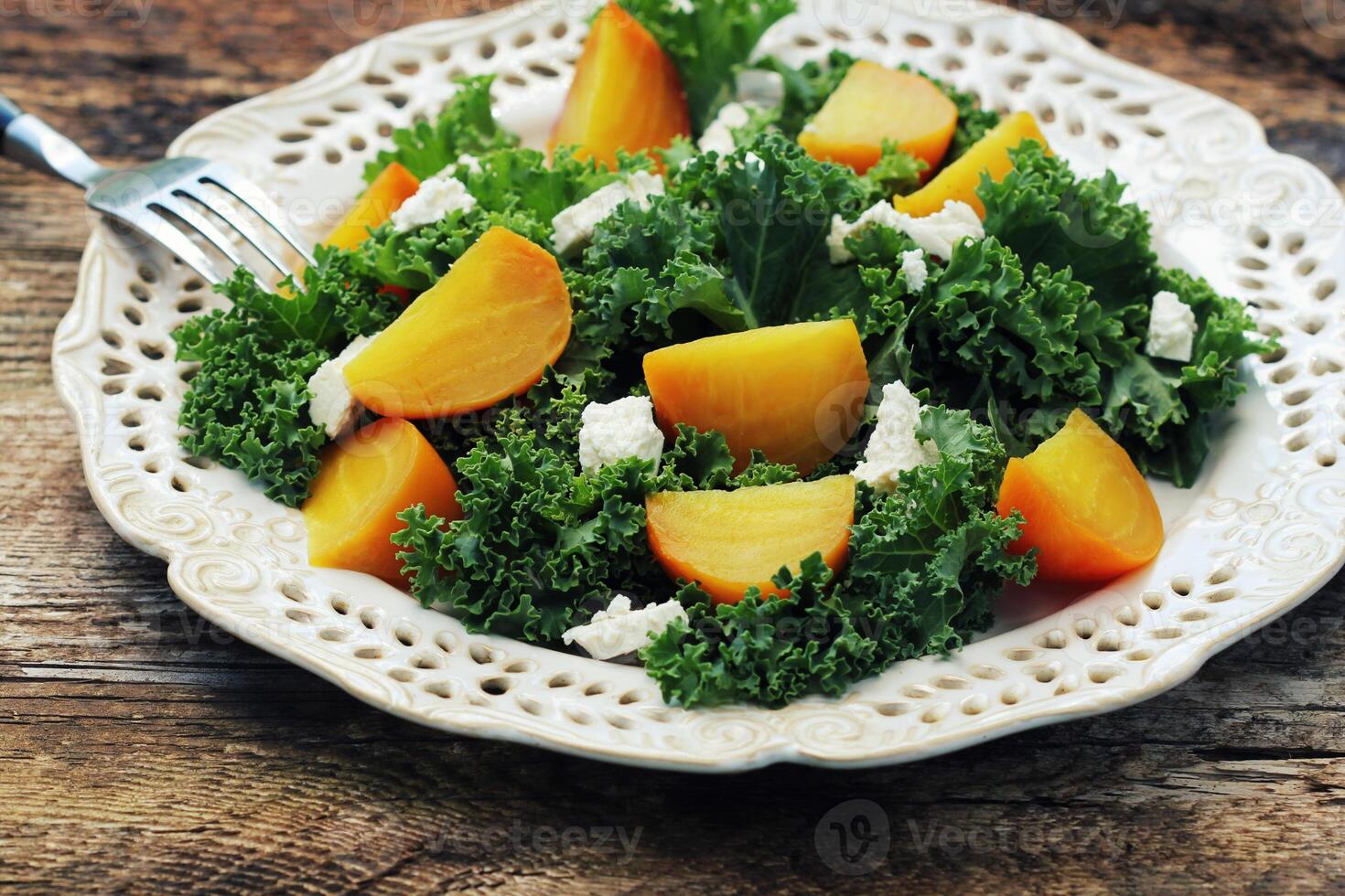 Healthy gollden beet salad with fresh kale lettuce, nuts, feta cheese on wooden background photo