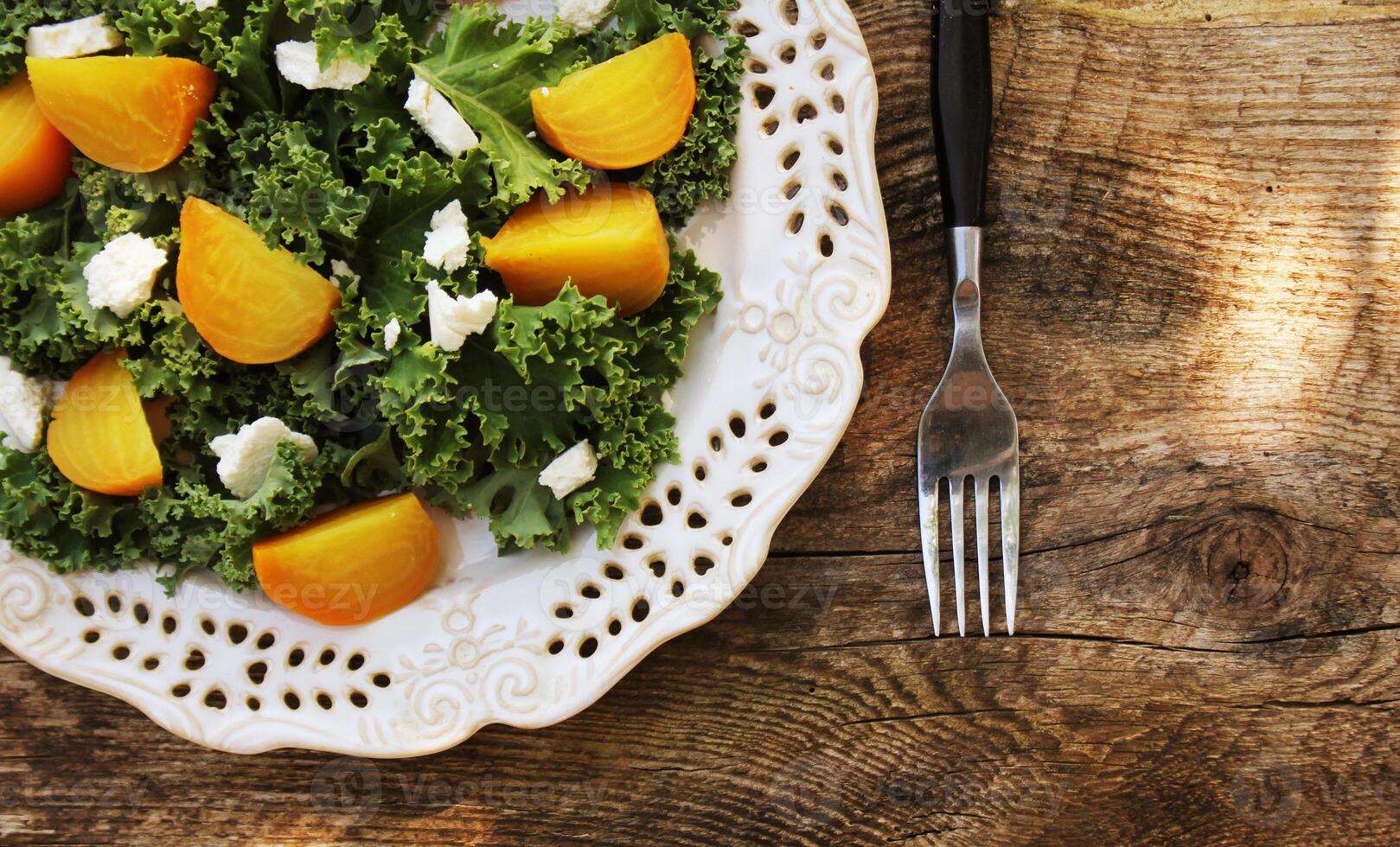 Healthy Beet Salad with fresh kale lettuce, nuts, feta cheese on wooden background photo