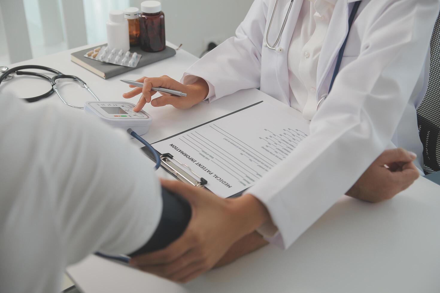 Male doctor uses a blood pressure monitor to check the body pressure and pulse of the patients who come to the hospital for check-ups, Medical treatment and health care concept. photo