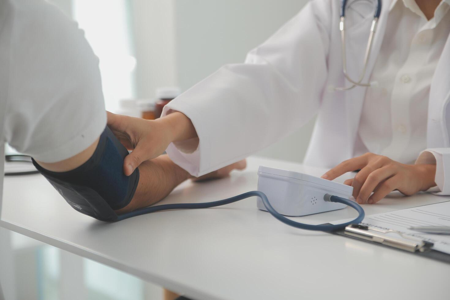 Male doctor uses a blood pressure monitor to check the body pressure and pulse of the patients who come to the hospital for check-ups, Medical treatment and health care concept. photo