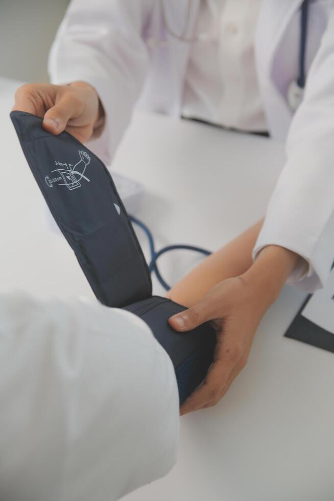 Male doctor uses a blood pressure monitor to check the body pressure and pulse of the patients who come to the hospital for check-ups, Medical treatment and health care concept. photo