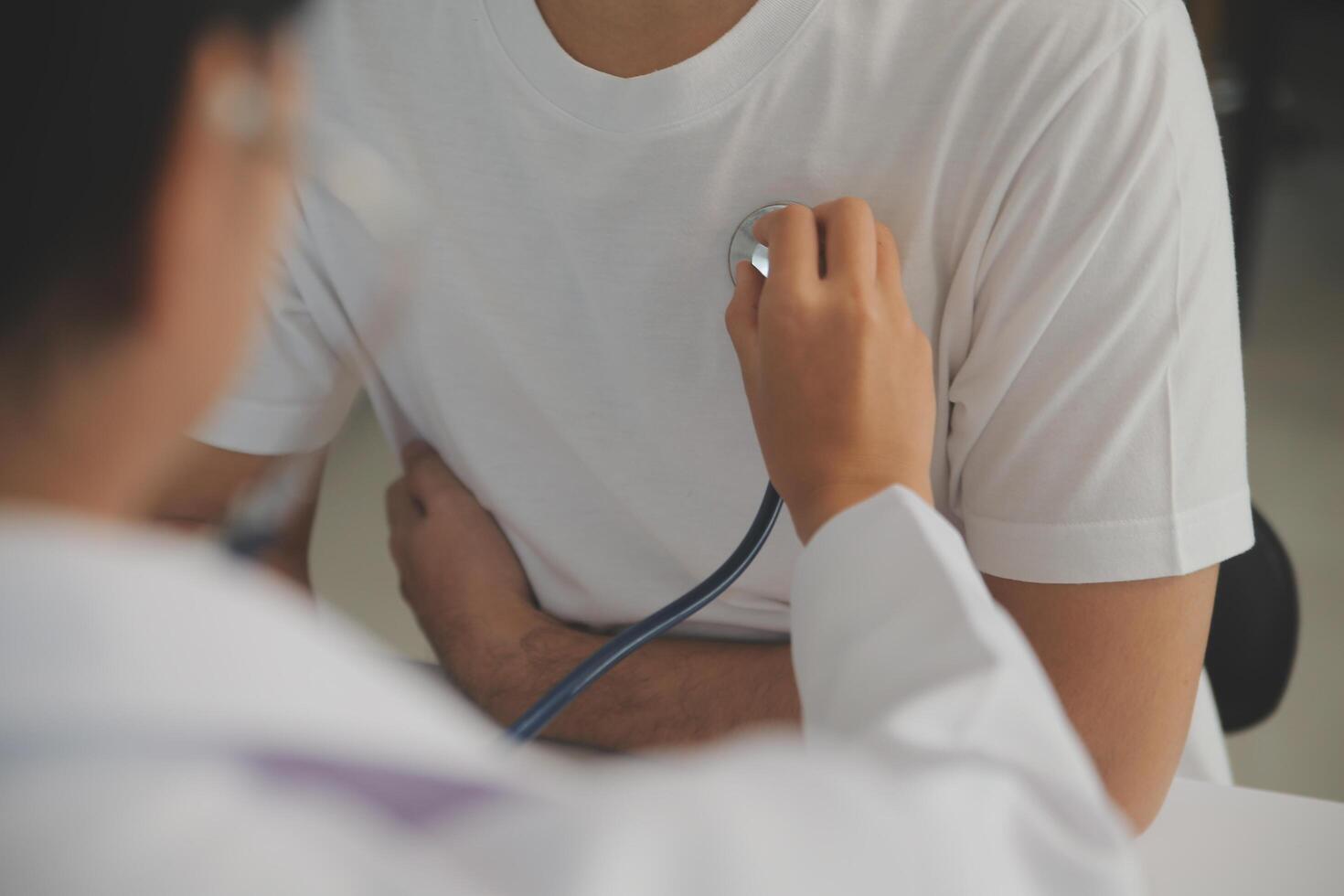 Young doctor is using a stethoscope listen to the heartbeat of the patient. Shot of a female doctor giving a male patient a check up photo