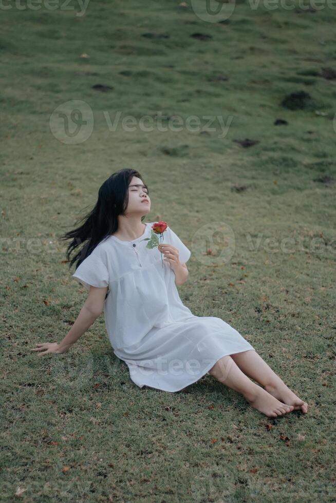 Portrait of a pretty young woman dressed in white dress holding rose flowers photo